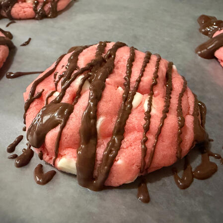 Chocolate Dipped Strawberry Cookie- A sweet, soft strawberry cookie filled with vanilla chips. Striped with milk chocolate for that perfect pop of flavor!